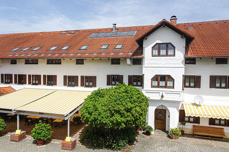 Unterkünfte Helles Gebäude mit rotem Dach und begrüntem Innenhof.