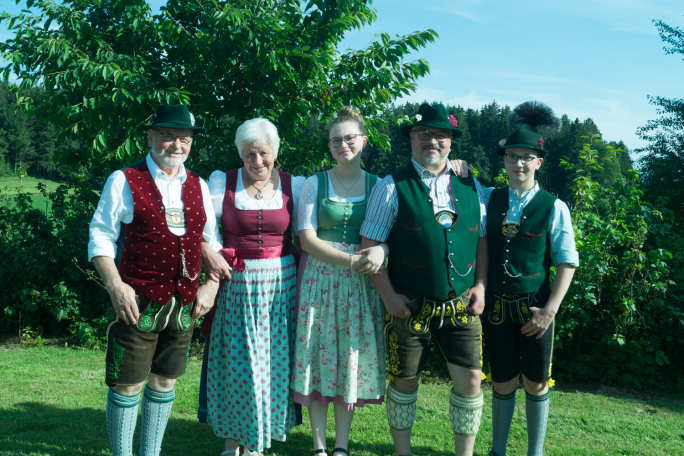 Familie Vodermaier in traditioneller Tracht stehen in einer grünen Landschaft.